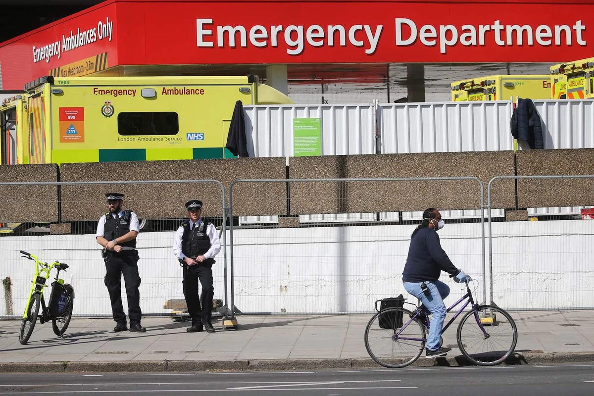 A cyclist passes police officers on duty outside St Thomas' Hospital in central London on April 7, 2020. (AFP)
