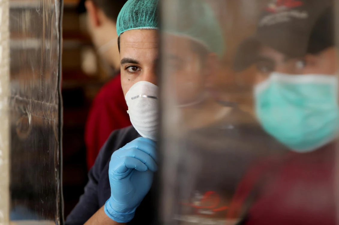 Palestinians, wearing masks as a preventive measure against coronavirus, work in a bakery in Gaza City, March 22, 2020. (Reuters)