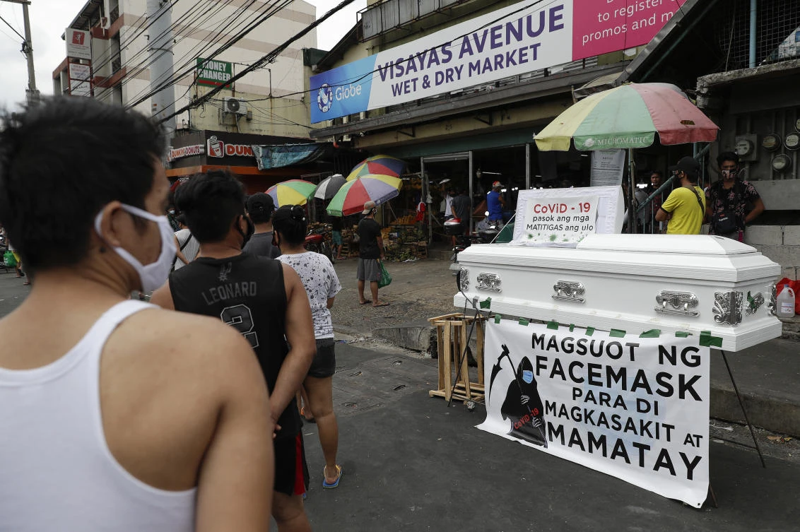 People line up beside an empty coffin with a bottom banner reading “Wear a face mask so you won’t get sick and die” as it is displayed outside a public market in Manila, Philippines on Thursday, April 9, 2020. (AP)