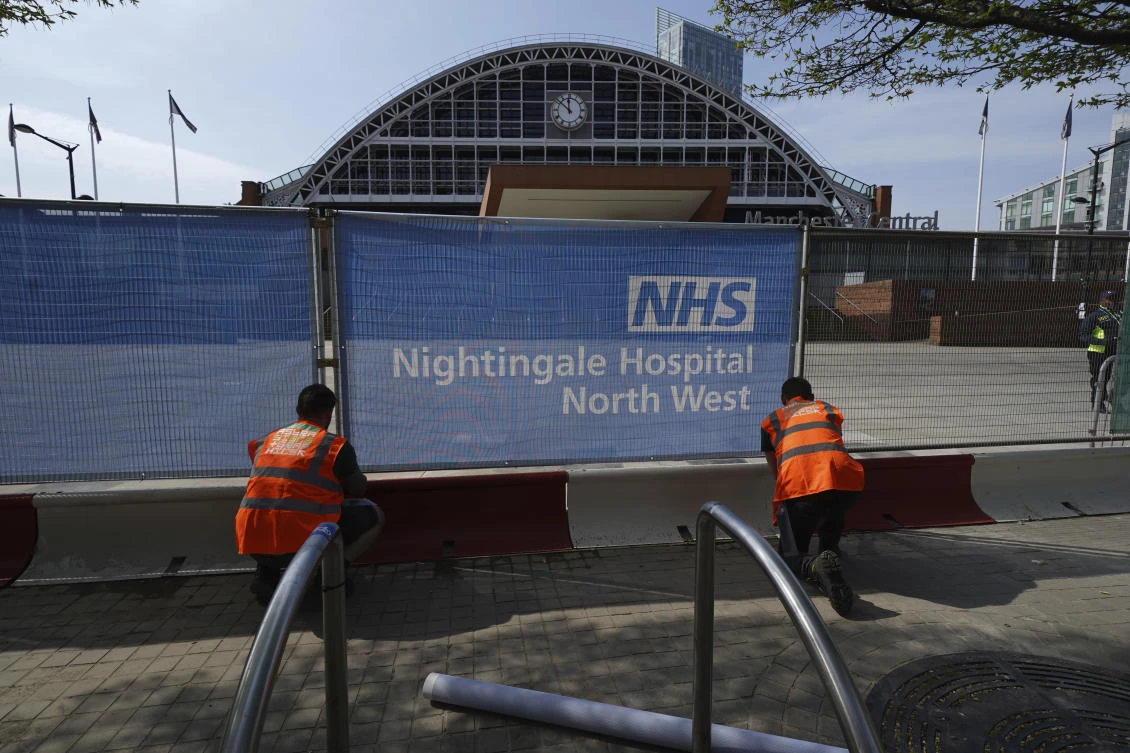 Workers put signs on fencing outside the newly setup coronavirus Nightingale Hospital North West at the G-MEX Manchester Central conference centre in Manchester, northern England, Thursday, April 9, 2020. (AP)