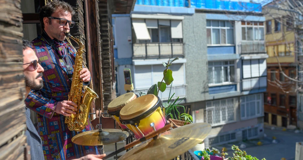 Turkish musician Alper Kalaycioglu and his roommate hold a concert at their Istanbul home for their social media fans amid quarantine measures. (AFP)
