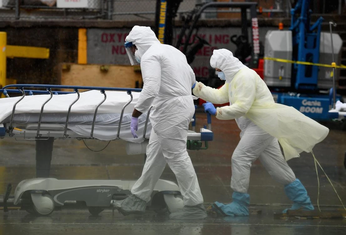 Medical personnel move a deceased patient to a refrigerated truck serving as make shift morgues at Brooklyn Hospital Center on April 09, 2020 in New York City. (AFP)