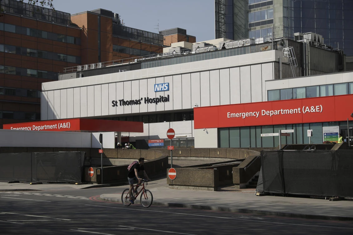 Workers who have been erecting and painting a fence over recent days to block the view of the ambulance entrance, stand outside St Thomas' Hospital in London, where British Prime Minister Boris Johnson is being treated for coronavirus, Friday, April 10, 2020. (AP)