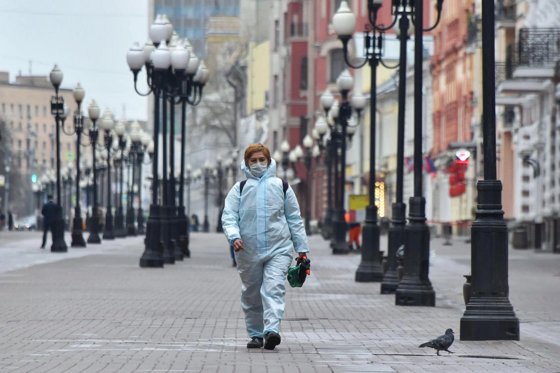 A woman wearing a protective suit carries googles and a disinfectant sprayer as she walks in downtown Moscow on April 8, 2020. (AFP)