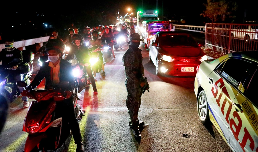 A long queue of motorists has formed as police officers attempt to check every individual's body temperature at a checkpoint placed amidst the lockdown of the country's capital to contain the spread of coronavirus, in the outskirts of Quezon City, Metro Manila, Philippines, March 15, 2020. (REUTERS)
