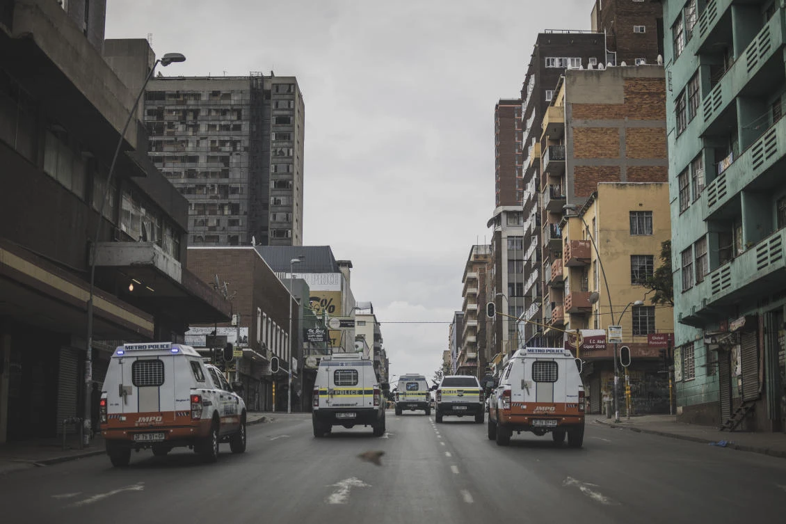 South African Police Service (SAPS) and Johannesburg Metro Police Department (JMPD) vehicles drive in Hillbrow, Johannesburg, on April 10, 2020, as they conduct an operation to enforce the country's lockdown. (AFP)