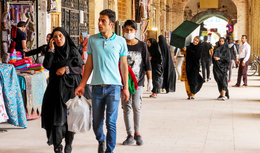 Iranians, some wearing personal protective equipment, walk past shops in the southeastern city of Kerman on April 11, 2020, amid the coronavirus (COVID-19) pandemic. (AFP)
