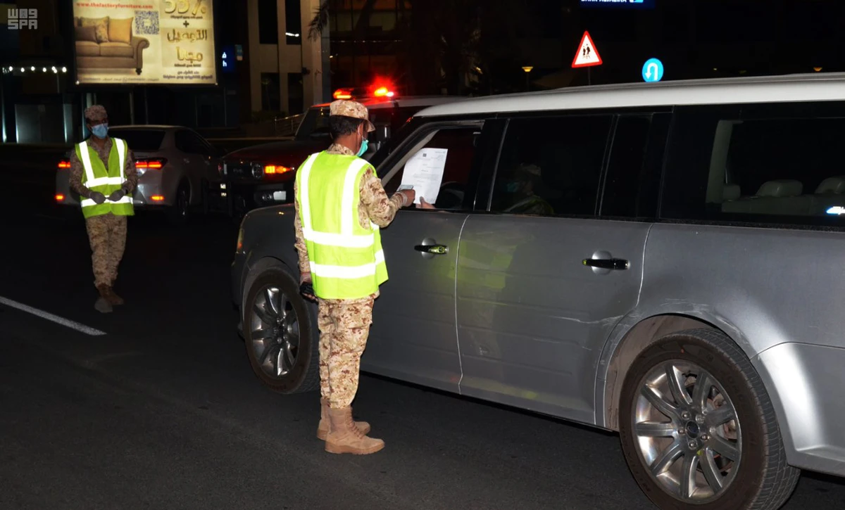 Police enforcing the curfew order check motorists along a road in Madinah on Saturday. (SPA)