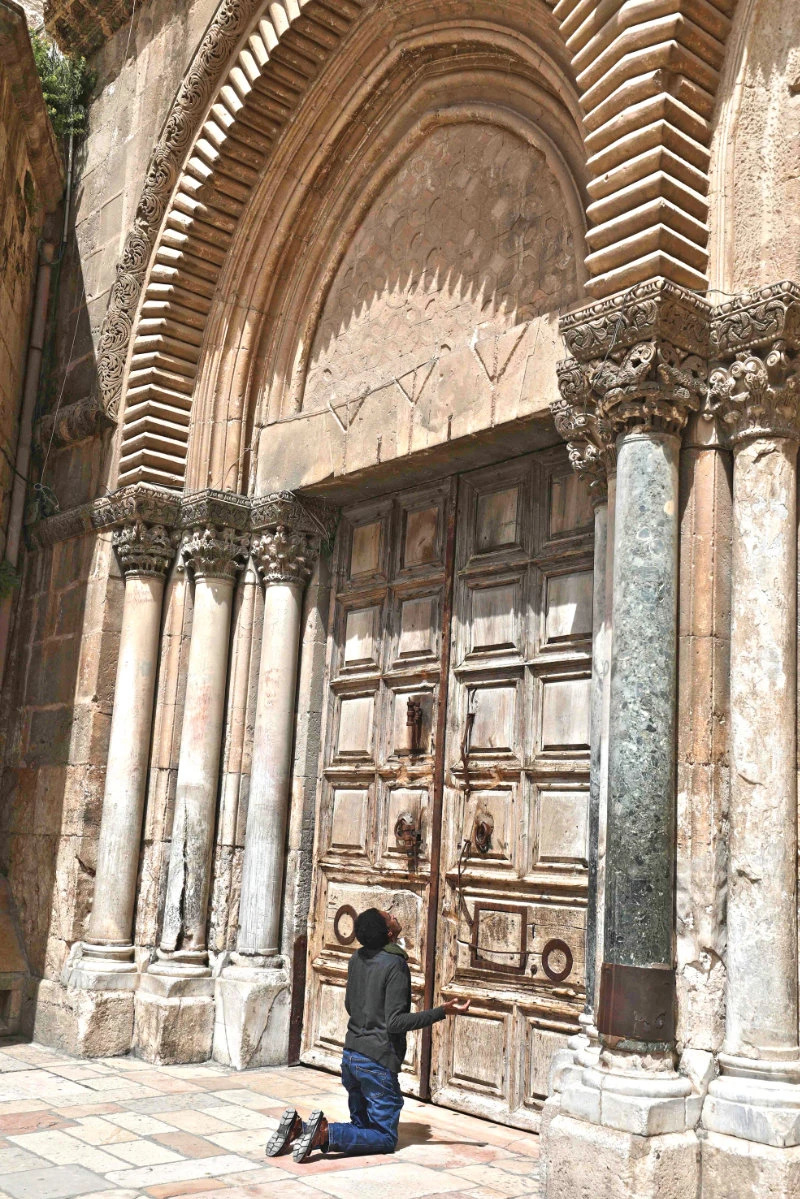 A man prays by the closed doors of the Church of the Holy Sepulchre in Jerusalem amid the COVID-19 pandemic. (AFP)