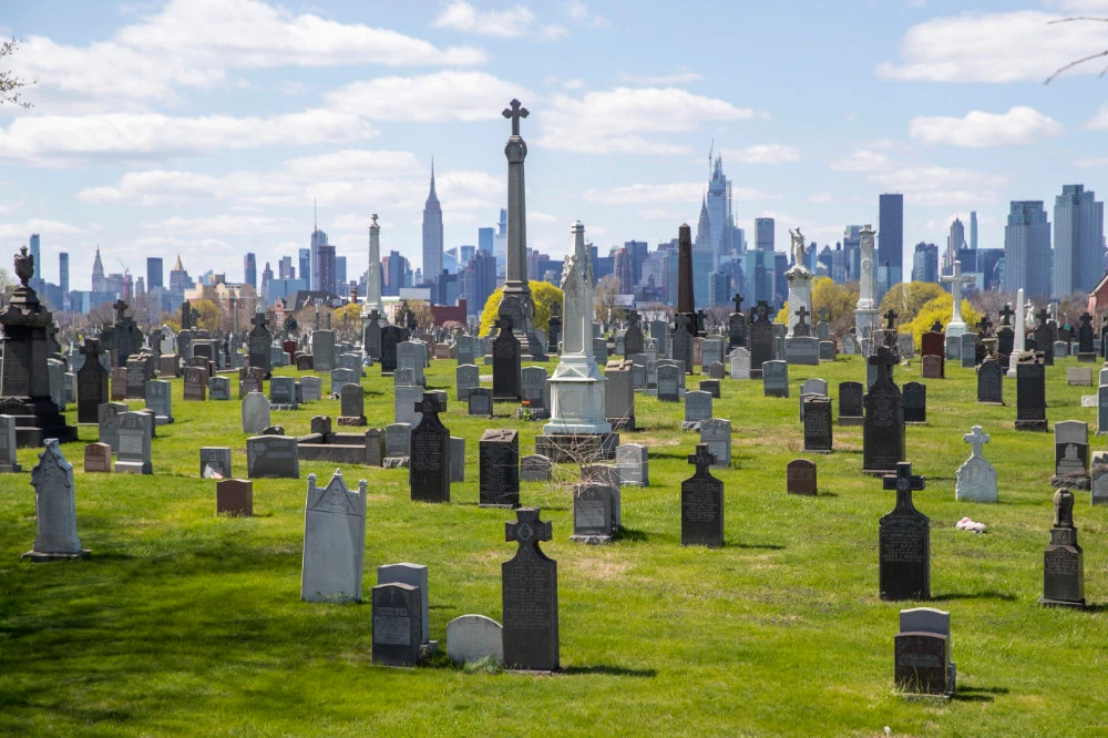 The Empire State building and the Manhattan skyline are seen behind the tombstones at Calvary Cemetery on April 11, 2020, in the Maspeth neighborhood of the Queens borough of New York.(AP Photo/Mary Altaffer)