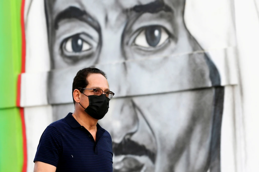 A Saudi man walks past a poster depicting Saudi King Salman bin Abdulaziz, after a curfew was imposed to prevent the spread of the coronavirus disease (COVID-19), in Riyadh, Saudi Arabia March 25, 2020. (Reuters)