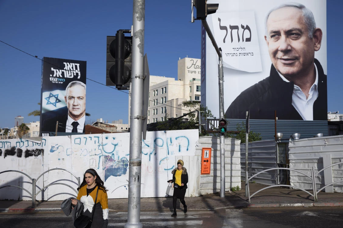 In this March. 1, 2020 file photo, people walk next to election campaign billboards showing Israeli Prime Minister Benjamin Netanyahu, right, and Benny Gantz, left, in Bnei Brak, Israel. (AP)