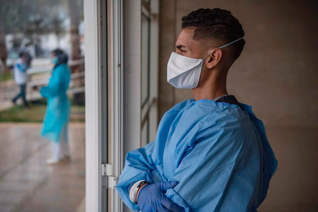 A members of the medical staff of a hospital where patients suffering from the Covid-19 disease caused by the novel coronavirus are treated, looks out from a window, in the city of Sale, north of the Moroccan capital Rabat, on April 12, 2020. (AFP)