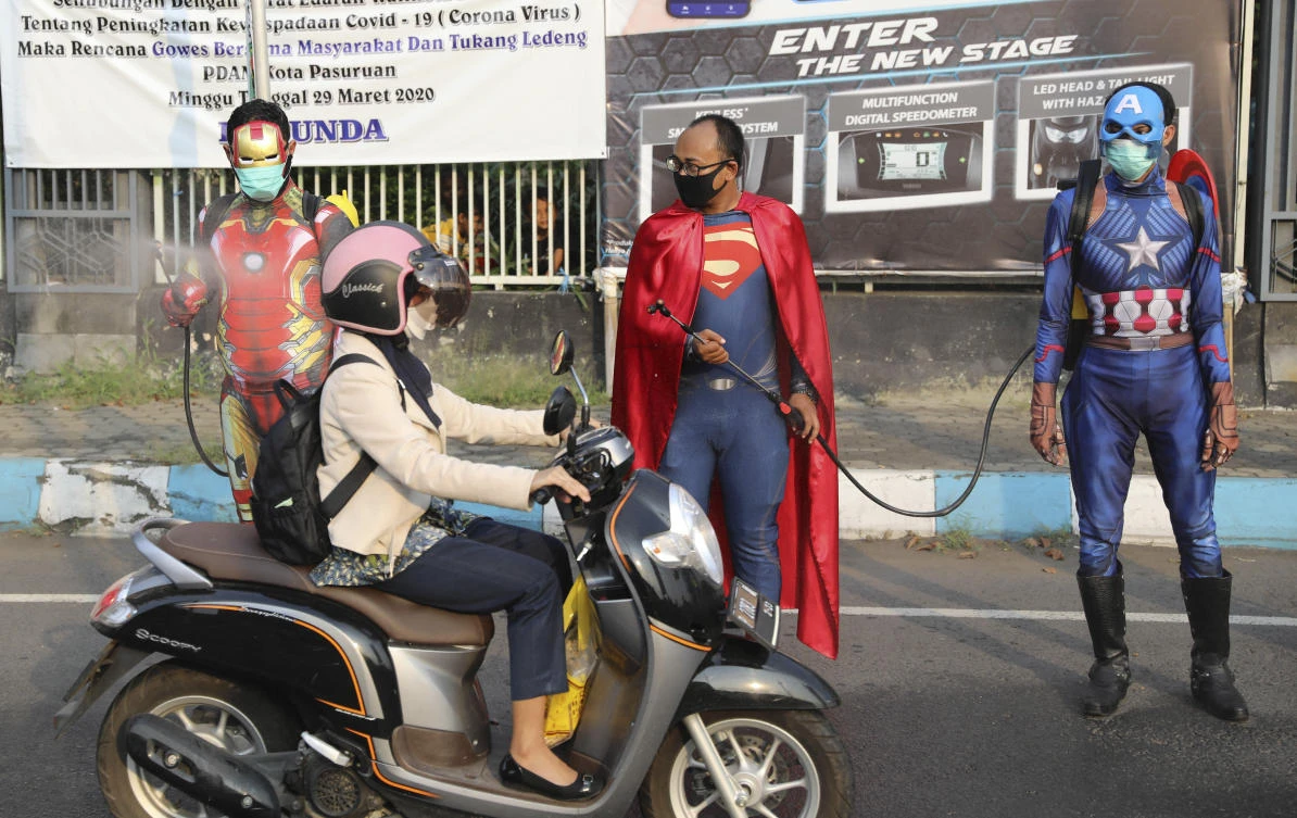 Above, police officers in superhero costumes spray disinfectant on motorists passing by in East Java, Indonesia on April 9, 2020. The total number of infections in the country is now at 4,557. (AP)