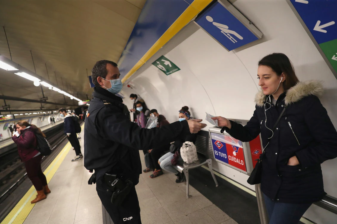 A police officer gives out free protective face masks at a metro station in Madrid, Spain on Monday, April 13, 2020. (Reuters)