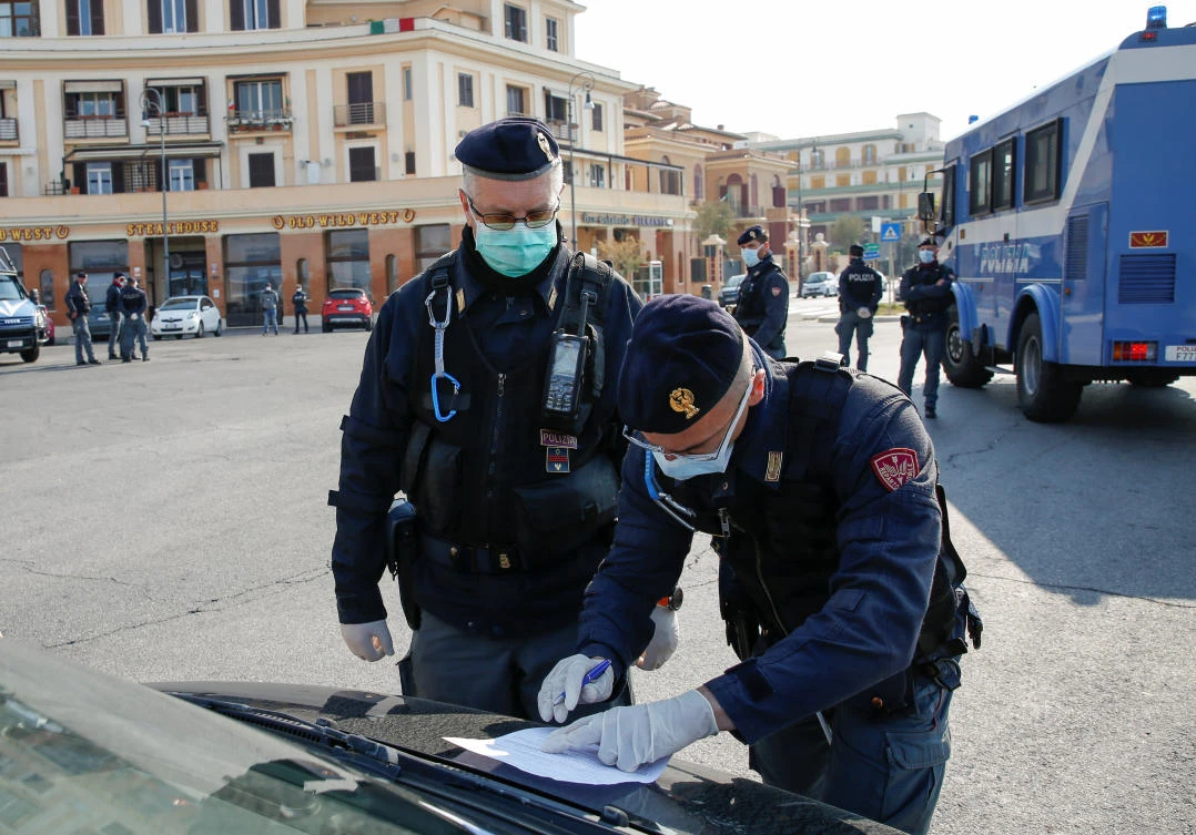 Police officers wearing protective face masks check documents of drivers, during the coronavirus disease (COVID-19) outbreak in Ostia, near Rome. (Reuters)