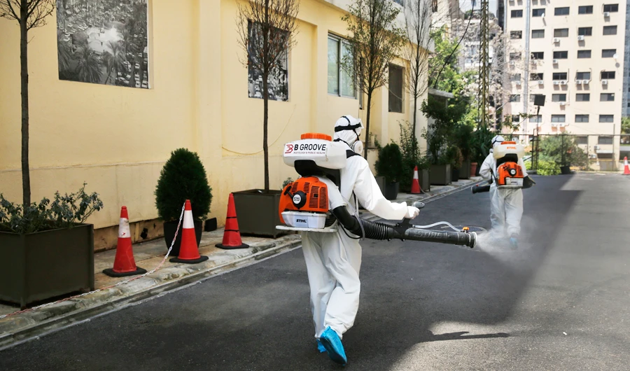 Workers spray disinfectant as a precaution against the coronavirus, outside a hotel where Lebanese passengers who arrived from abroad will get tested for the infection in Beirut on Sunday. (AP)