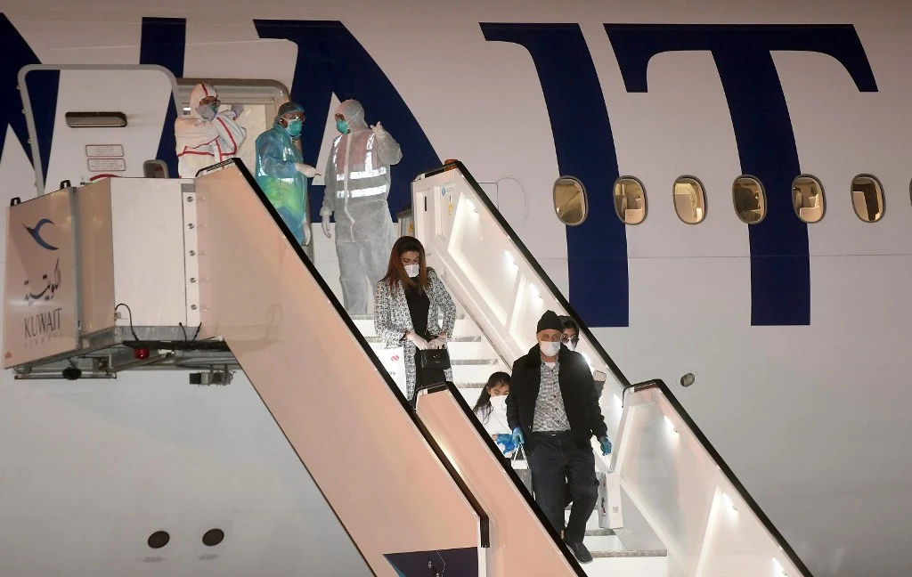 Above, Kuwaiti citizens repatriated from Germany leave an aircraft that landed at the Kuwait International Airport on March 26, 2020. (AFP file photo)