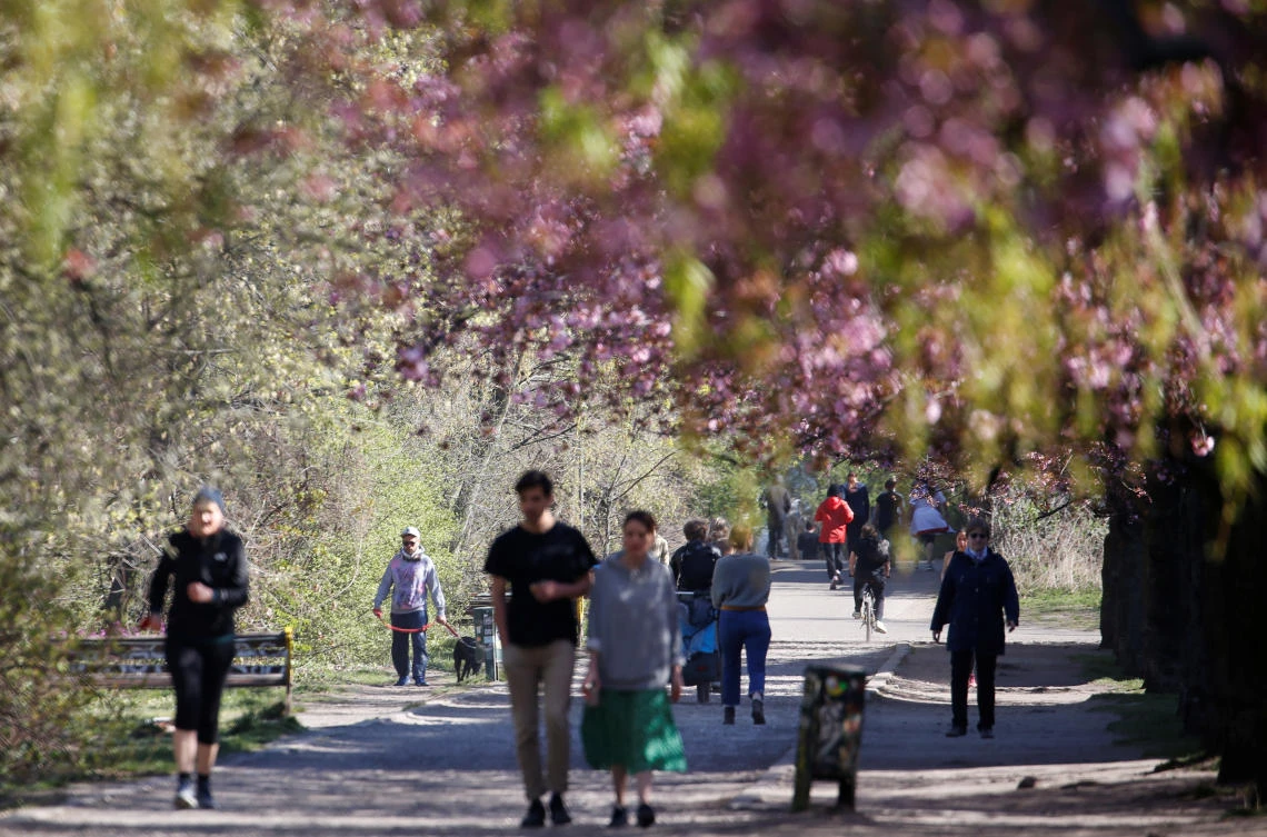 Above, people walk under blooming cherry blossoms in a park in the Berlin district of Treptow on Easter Sunday. The number of new infections in Germany rose after four days of decline. (Reuters)