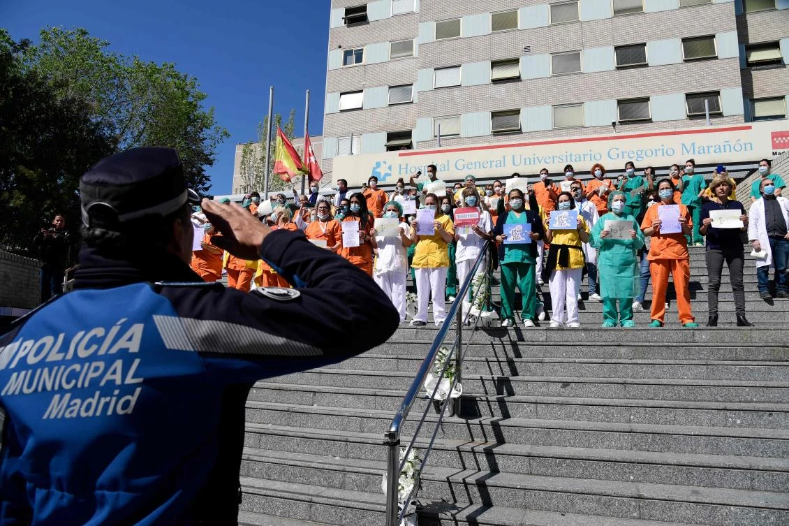 A policeman salutes heathcare workers outside the Gregorio Maranon Hospital in Madrid on April 12, 2020. The number of new confirmed infections in Spain rose by over 5,000. (AFP)