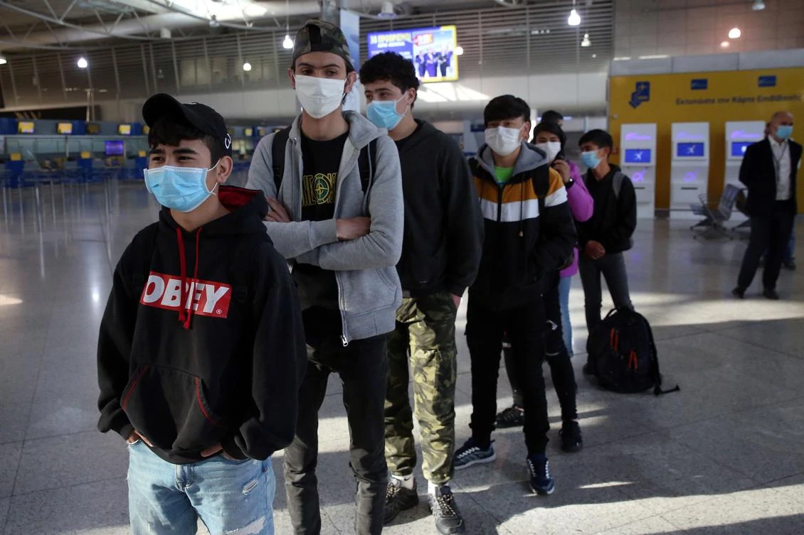 Unaccompanied minor refugees wearing protective masks, who were living at the overcrowded migrant camps on the islands, wait for their documents before boarding at the International Airport of Athens, to travel on a special flight to Luxembourg, on April 15, 2020. (AFP)