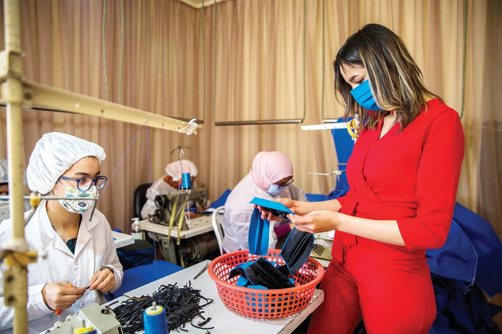 Clothing factory CEO Khouloud Guesmi, right, checks a face mask at her production line outside Tunis after she repurposed her fashion business. Tunisia is in lockdown until at least Sunday. (AP)