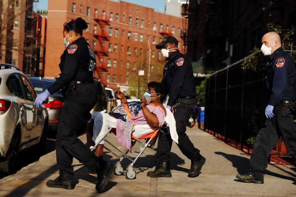 A New York City Fire Department (FDNY) Emergency Medical Technician (EMT) wearing personal protective equipment assist a woman who was having difficulty breathing during ongoing outbreak of the coronavirus disease (COVID19) in New York on April 15, 2020. (REUTERS/Lucas Jackson)