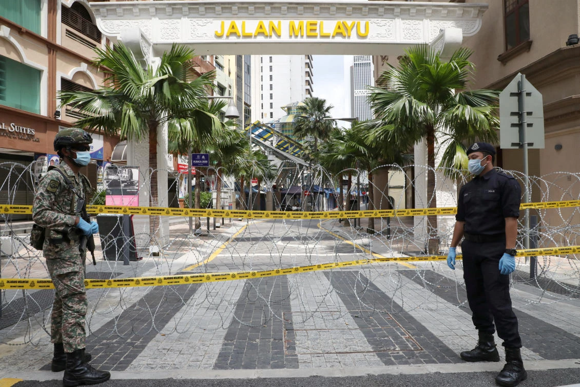 A soldier and a police officer guard an entrance of the red zone under enhanced lockdown in Kuala Lumpur, Malaysia on April 15, 2020. (Reuters)