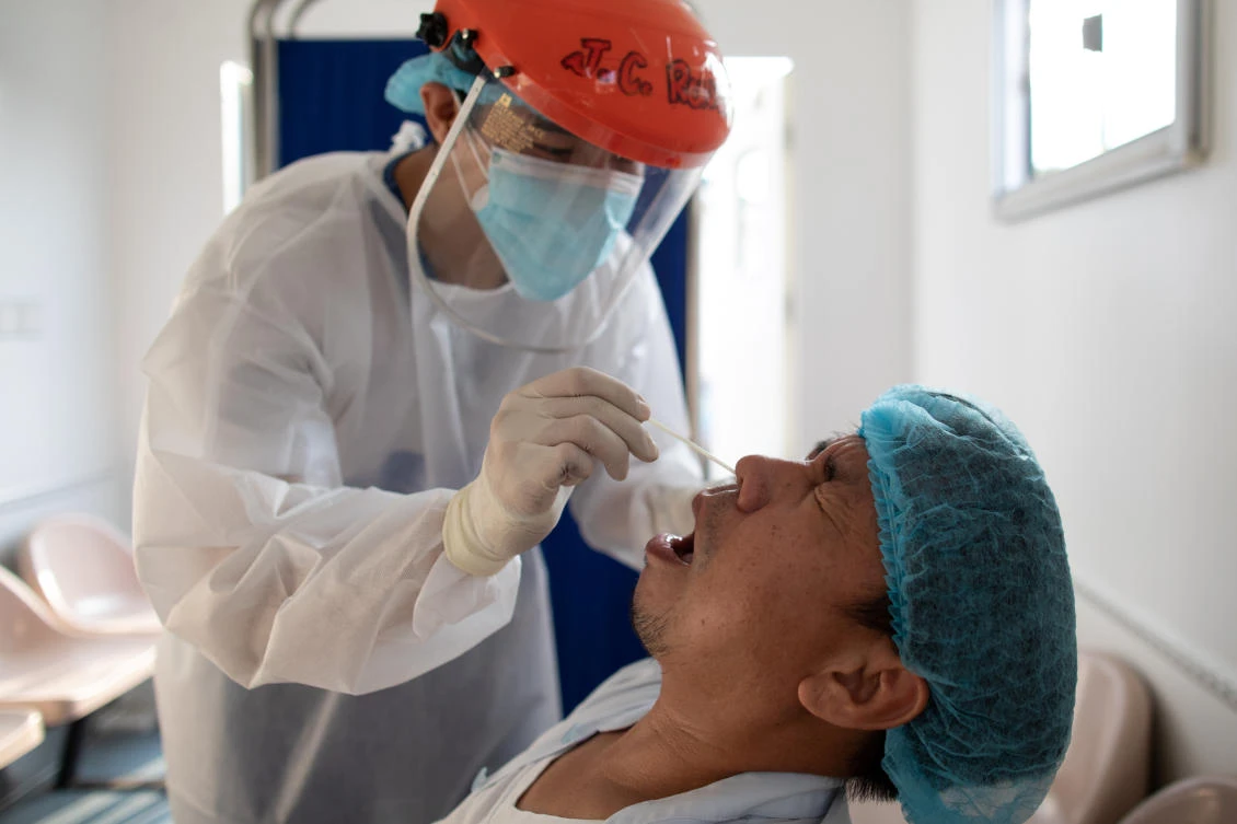 Above, a nurse gets a swab from a health worker as the Philippines ramped up testing for coronavirus disease. (Reuters)