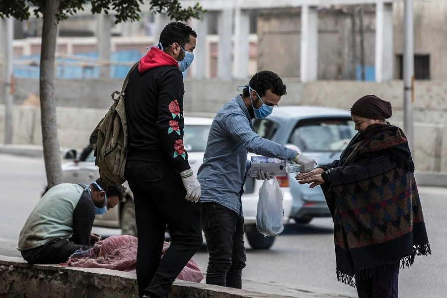 Volunteers disinfects the hands of a woman in a street in the Egyptian capital Cairo on March 20, 2020. (File/AFP)