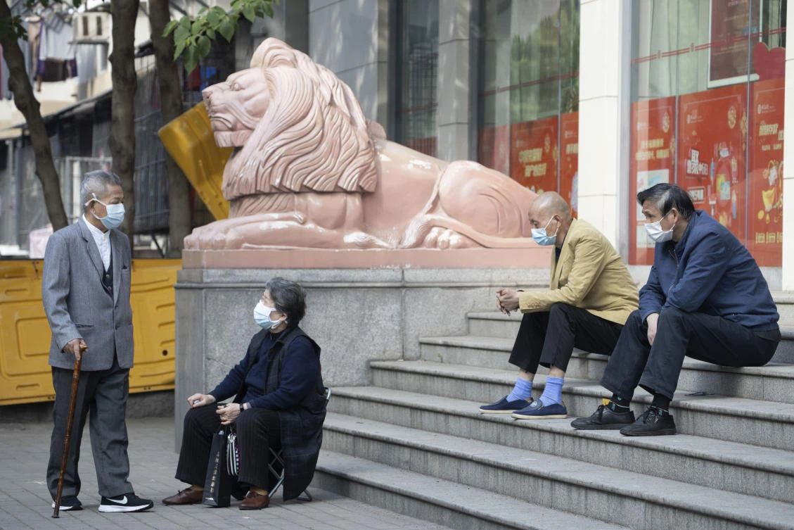 Elderly residents wearing masks against the coronavirus wait outside a bank in Wuhan in central China’s Hubei province, April 16, 2020. (AP Photo)