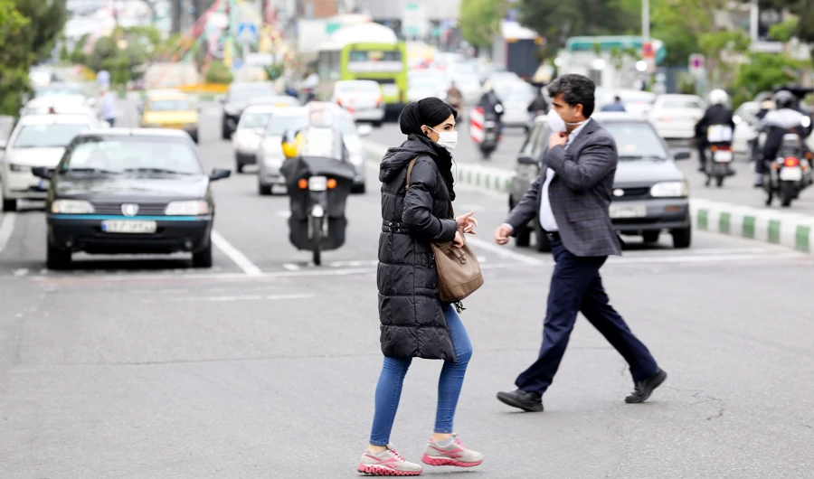 Iranians wearing protective masks cross a main road in Tehran on April 13, 2020 during the coronavirus COVID-19 pandemic. Iran said on April 14 that the number of lives lost in the country to the novel coronavirus dropped to double figures for the first time in one month. (AFP)