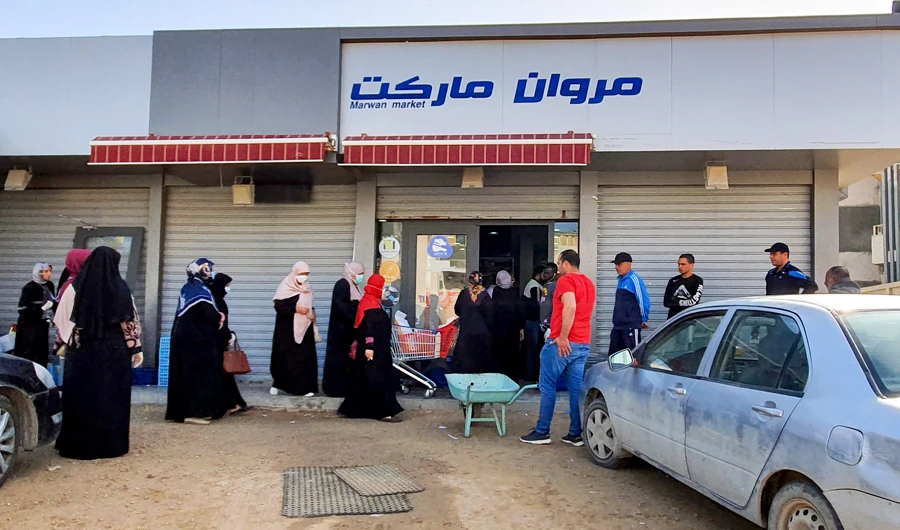 Libyans queue outside a supermarket, during a curfew announced to fight the spread of COVID-19 in the capital Tripoli on Sunday. (AFP)