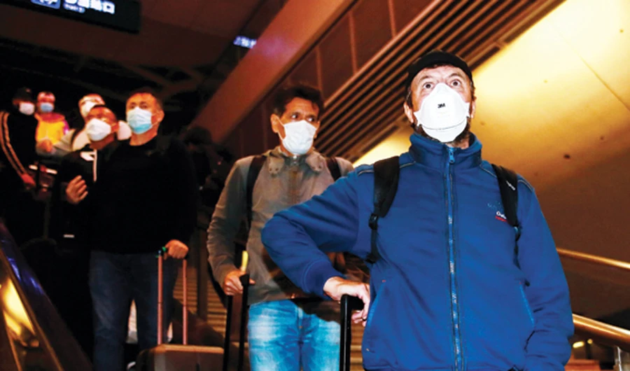 Wuhan Zall football team coach Jose Gonzalez, right, arrives on Saturday night with his players and coaching staff at the railway station in Wuhan. (AFP)