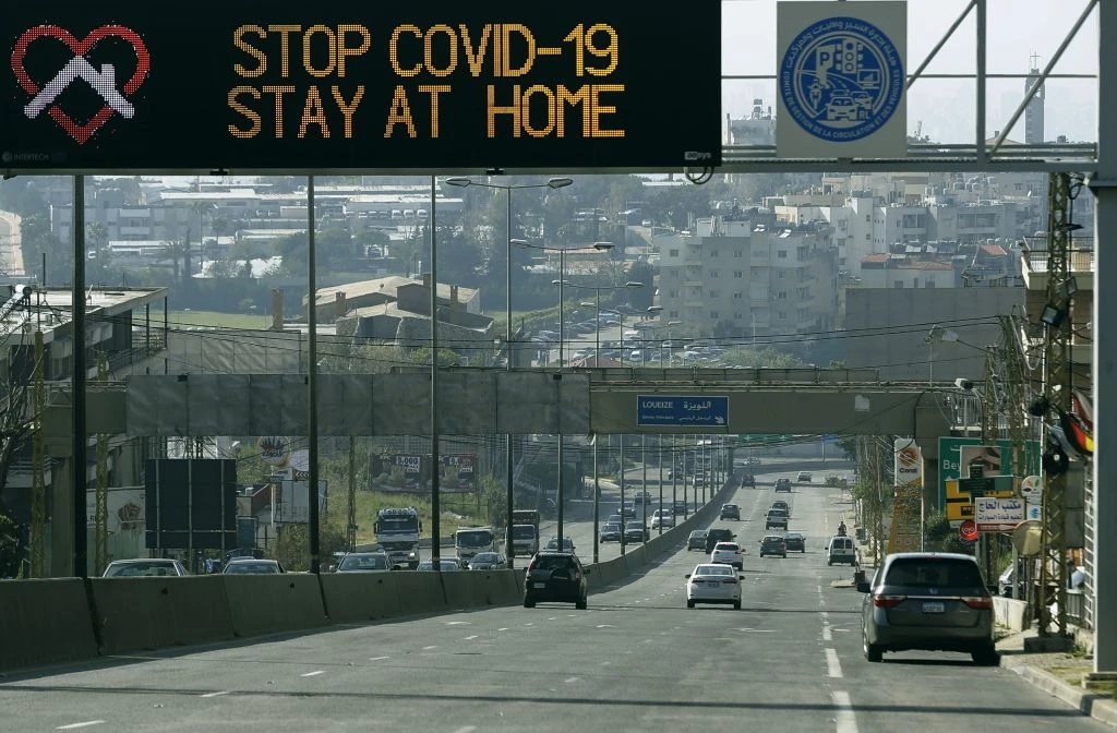 Cars cross under a road sign calling on people to stay at home to contain the spread of COVID-19, on the Beirut-Damascus international highway, east of Beirut, April 14, 2020. (Getty Images)