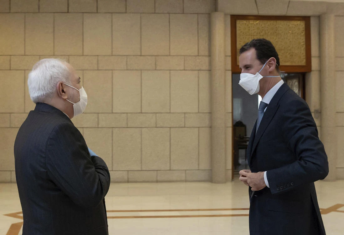 In this photo released by the Syrian official news agency SANA, Syrian President Bashar Assad, right, wears a mask to help protect from the coronavirus, as he speaks with Iranian Foreign Minister Mohammad Javad Zarif, who also wore a mask and gloves, in Damascus. (AP)