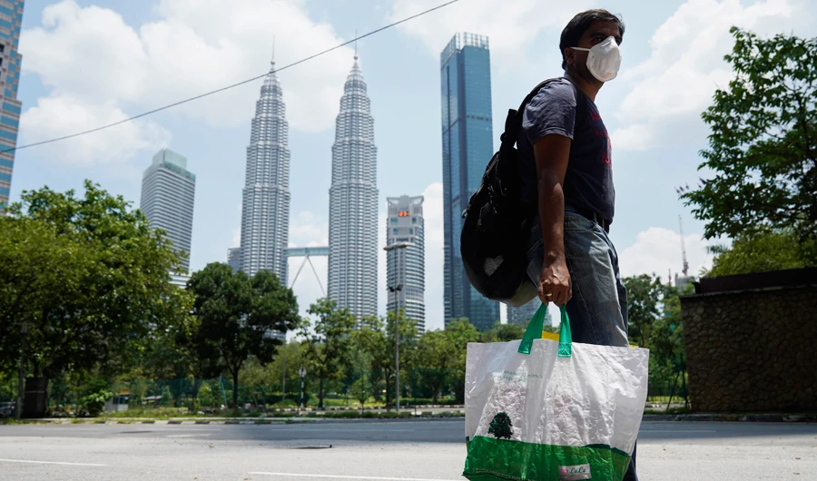 A man wearing a face mask passes the Twin Towers during the movement control order issued to help curb the outbreak of the coronavirus disease in Kuala Lumpur, Malaysia, Sunday, April 19, 2020. (AP)