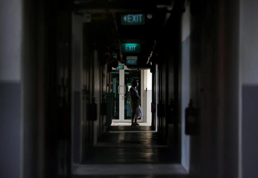 Above, a migrant worker looks out from a walkway at a dormitory declared as an isolation area, during the coronavirus outbreak in Singapore on April 21, 2020. (Reuters)