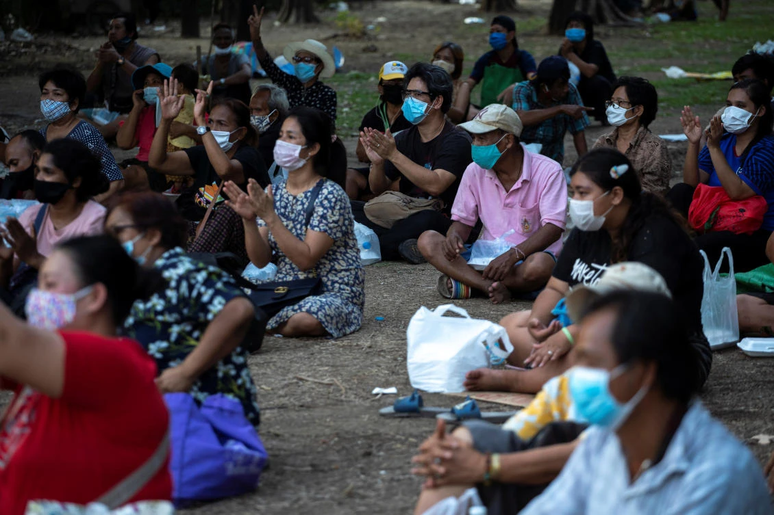 Thai residents affected by anti-coronavirus disease measures clap after receive free meals at a park in Bangkok on April 21, 2020. (Reuters)