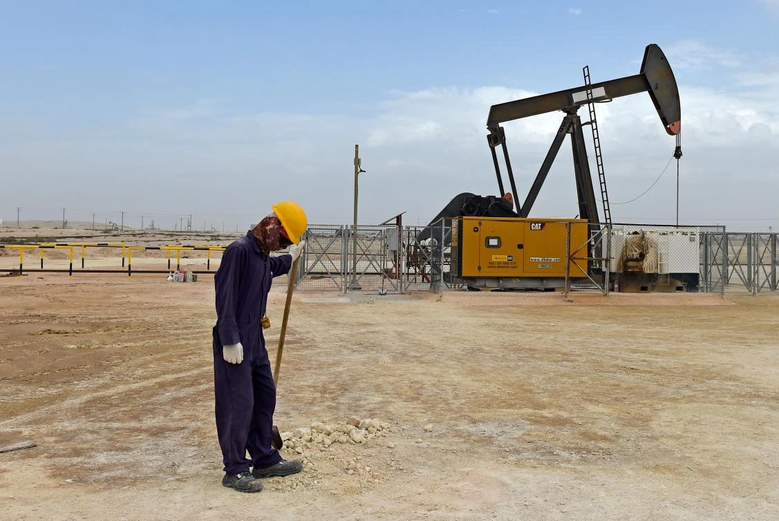 A worker stands across a pumpjack operating in the desert oil fields of Sakhir in southern Bahrain. (AFP)