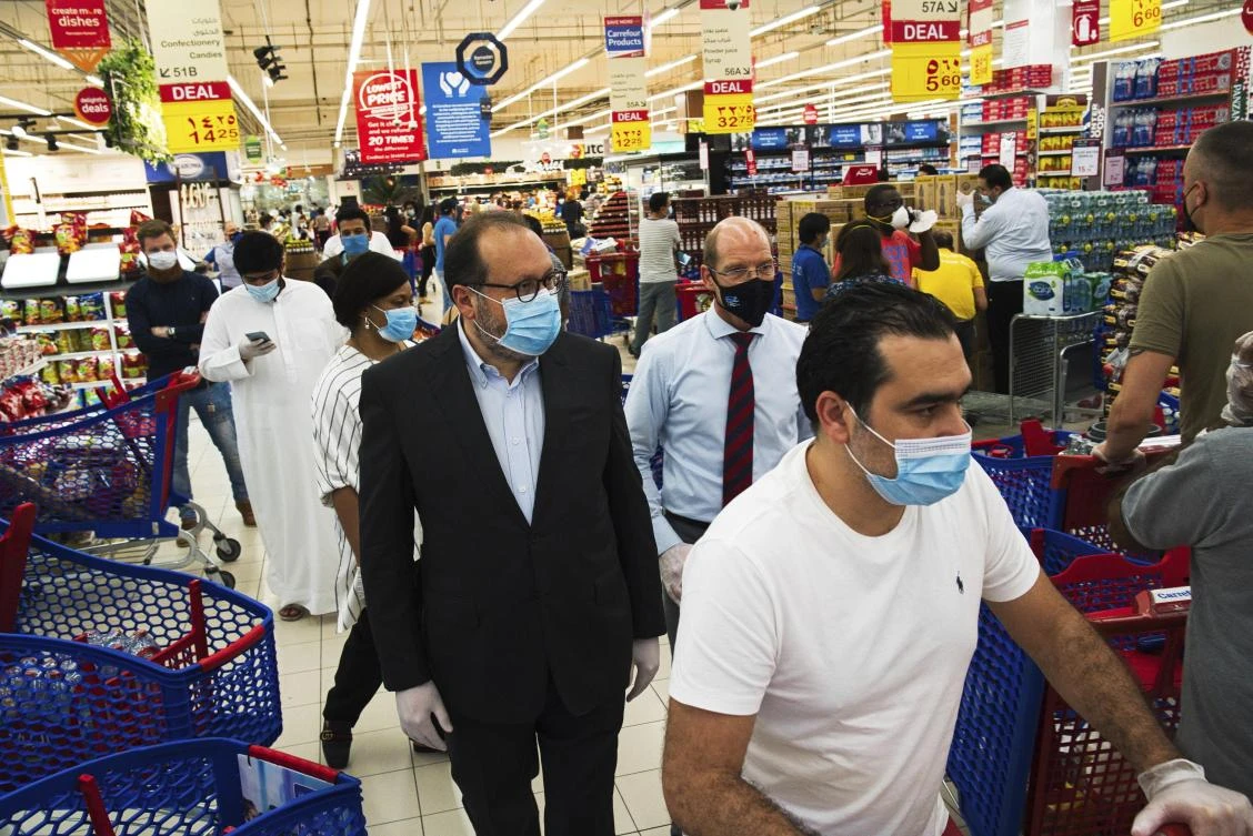 Majid Al Futtaim CEO Alain Bejjani, center left, and store manager Arnaud Bouf, center, walk through heavy shopping traffic during the coronavirus pandemic in the world's busiest Carrefour supermarket, at the Mall of the Emirates in Dubai. (AP)