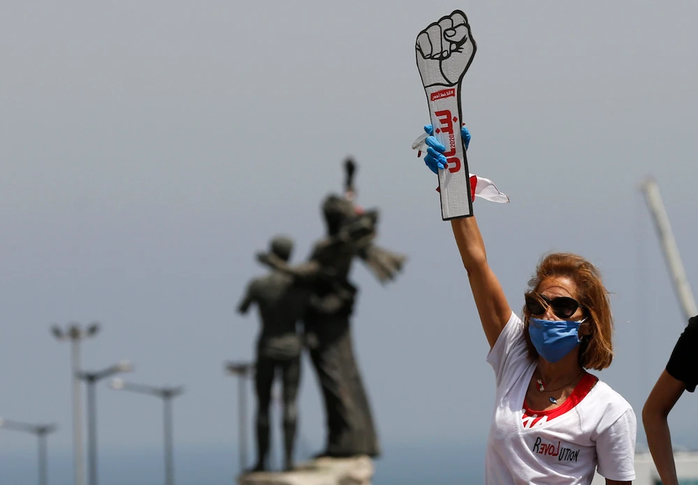 An anti-government protester holds a cardboard revolutionary fist during a driving convoy protest through the streets of Beirut to express rejection of Lebanon’s political leadership, April 22, 2020. (AP Photo)