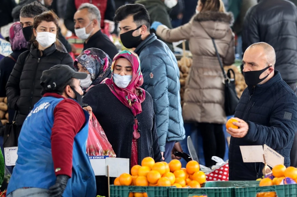 People wear protective masks while they shop at a street market in Ankara on April 22, 2020 ahead of a four-day lockdown from April 23, 2020. (AFP)