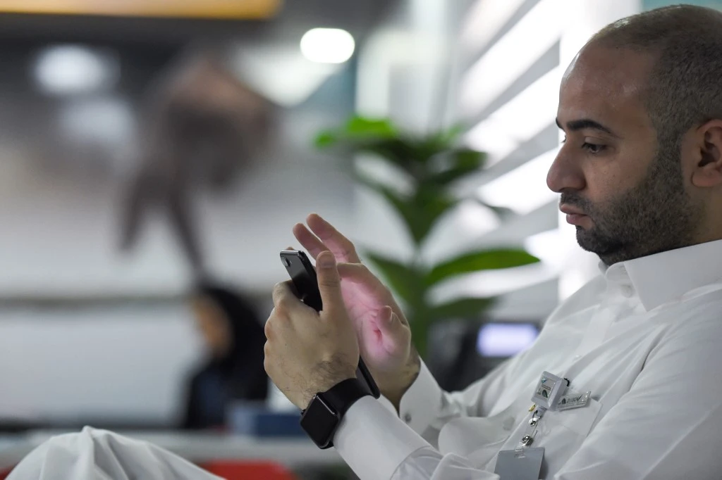 Measures taken by the Saudi government to allow delivery apps to work during curfew hours have attracted new customers to the services. Above, a Saudi employee checking his cell phone at his office in the capital Riyadh. (AFP file photo)