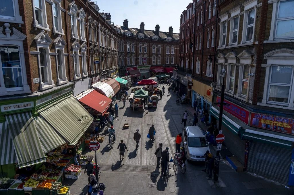Above, shoppers walk at a nearly empty Electric Avenue in Brixton, south London on April 23, 2020. (AFP)