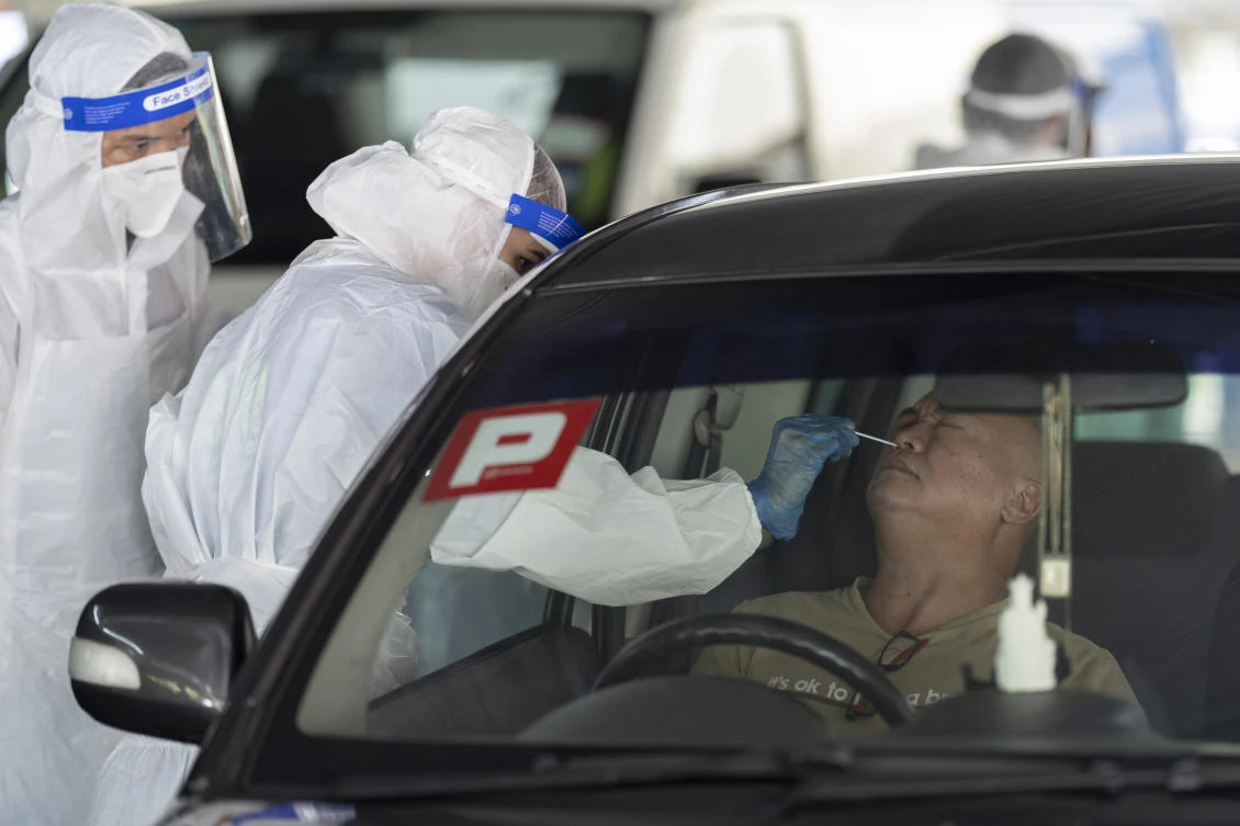 The daily rise in coronavirus cases in Malaysia remains in double digits for the eighth straight day. Above, a health worker collects a sample from a man on Thursday, April 23, 2020. (AP)
