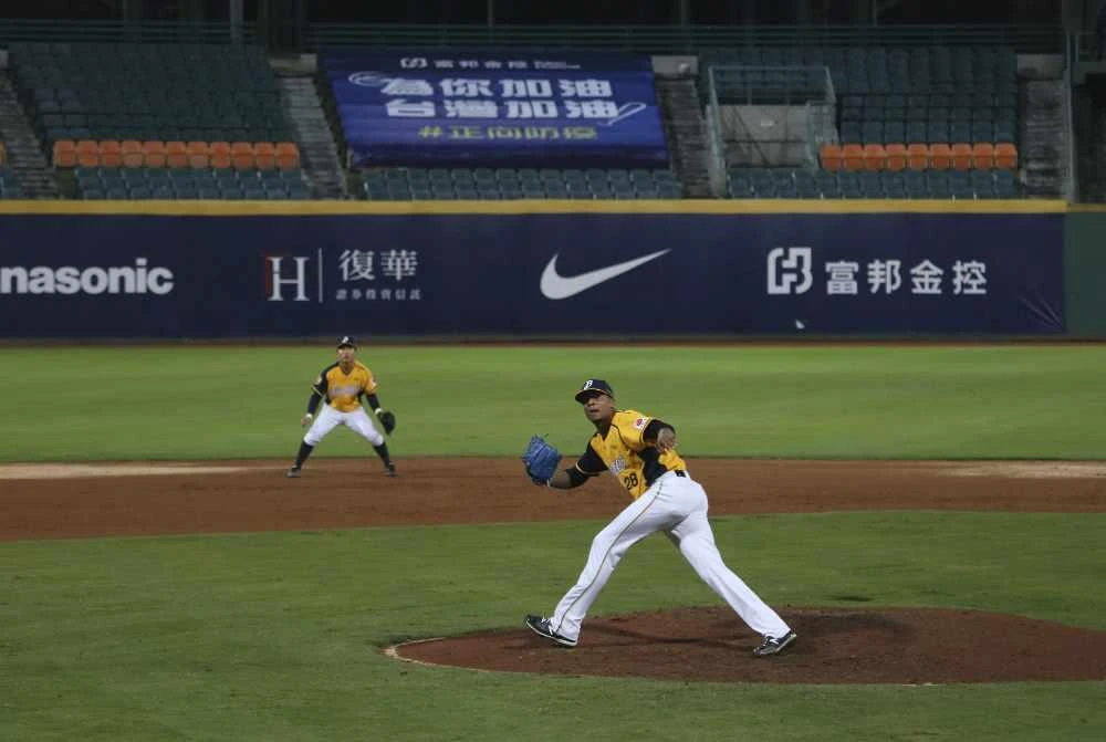 This April 24, 2020, photo, shows Chinatrust Brothers players during a game against Fubon Guardians with no audience at Xinzhuang Baseball Stadium in New Taipei City, Taiwan. (AP Photo/Chiang Ying-ying)