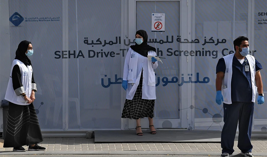 Medical volunteers wait outside a drive-through COVID-19 coronavirus testing centre in Al Khawaneej district of Dubai on April 09, 2020. (AFP photo)