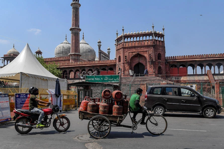 A worker (C) transporting cooking gas cylinders on a cart rides past the Jama Masjid on the eve of the Muslim holy month of Ramadan during a government-imposed nationwide lockdown as a preventive measure against the COVID-19 coronavirus, in New Delhi on April 24, 2020. (AFP)
