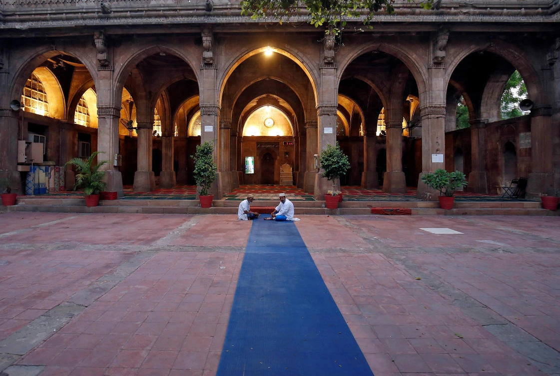 Two men eat their iftar meals inside an almost empty Sidi Saiyyed mosque Ramadan, during a nationwide lockdown to slow the spread of the coronavirus disease (COVID-19), in Ahmedabad, India, April 26, 2020. (Reuters)